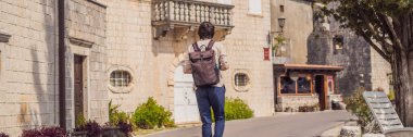 BANNER, BANNONG eski erkek turist güneşli bir günde Eski Perast kasabasında renkli caddenin tadını çıkarıyor. Karadağ 'a seyahat. Ünlü tarihi Perast kasabasının manzara manzarası.