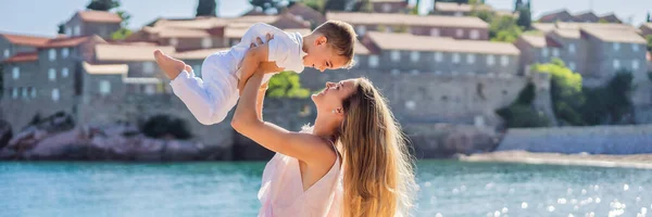 BANNER, LONG FORMAT Mother and son tourists on background of beautiful view St. Stephen island, Sveti Stefan on the Budva Riviera, Budva, Montenegro. Travel to Montenegro concept.