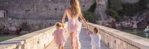 BANNER, LONG FORMAT Mother and two children daughter and son tourists on background of beautiful view St. Stephen island, Sveti Stefan on the Budva Riviera, Budva, Montenegro. Travel to Montenegro