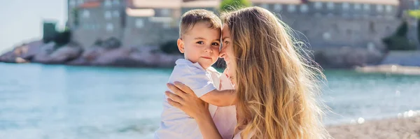 BANNER, LONG FORMAT Mother and son tourists on background of beautiful view St. Stephen island, Sveti Stefan on the Budva Riviera, Budva, Montenegro. Travel to Montenegro concept.