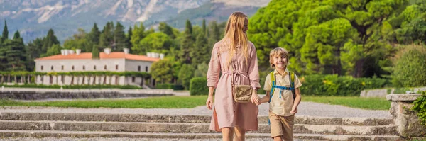 BANNER, LONG FORMAT Mom and son tourists walking together in Montenegro. Panoramic summer landscape of the beautiful green Royal park Milocer on the shore of the the Adriatic Sea, Montenegro.