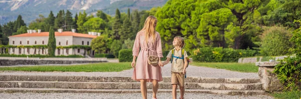 BANNER, LONG FORMAT Mom and son tourists walking together in Montenegro. Panoramic summer landscape of the beautiful green Royal park Milocer on the shore of the the Adriatic Sea, Montenegro.