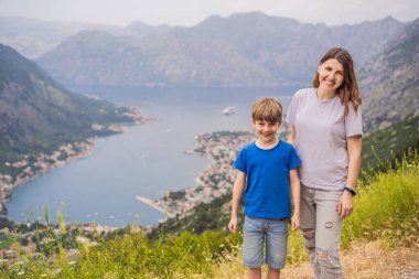 Anne ve oğul gezginler Kotor 'un manzarasından hoşlanırlar. Karadağ. Kotor Körfezi, Kotor Körfezi, Boka Kotorska ve eski şehrin duvarları. Karadağ 'a seyahat. Kotor 'un tahkimatları UNESCO Dünyasında