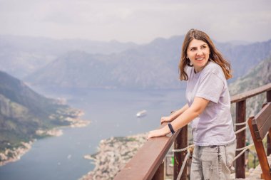 Kadın turist Kotor 'un manzarasından hoşlanıyor. Karadağ. Kotor Körfezi, Kotor Körfezi, Boka Kotorska ve eski şehrin duvarları. Karadağ 'a seyahat. Kotor 'un tahkimatları UNESCO Dünya Mirası' nda.