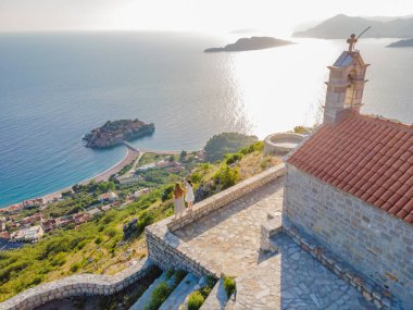 İki kadın turist, Karadağ 'ın Budva Riviera kentindeki St. Stephen adasının güzel manzarasına bakıyor. Karadağ 'a Seyahat.