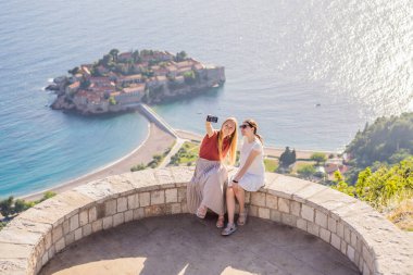 İki kadın turist, Karadağ 'ın Budva Riviera kentindeki St. Stephen adasının güzel manzarasına bakıyor. Karadağ 'a Seyahat.
