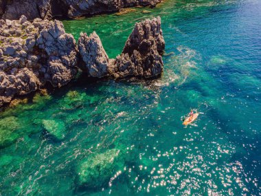 Genç kadınlar, Karadağ 'ın mavi sularında ayakta kürek çekerken eğleniyorlar. - Süper. Kayaların yanındaki sörf tahtasındaki kız eğitimi..