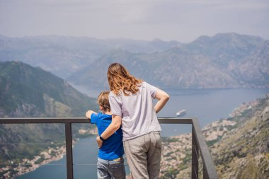 Anne ve oğul gezginler Kotor 'un manzarasından hoşlanırlar. Karadağ. Kotor Körfezi, Kotor Körfezi, Boka Kotorska ve eski şehrin duvarları. Karadağ 'a seyahat. Kotor 'un tahkimatları UNESCO Dünyasında