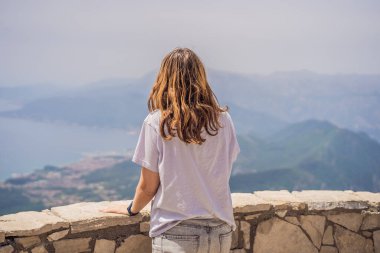 Kadın turist Kotor 'un manzarasından hoşlanıyor. Karadağ. Kotor Körfezi, Kotor Körfezi, Boka Kotorska ve eski şehrin duvarları. Karadağ 'a seyahat. Kotor 'un tahkimatları UNESCO Dünya Mirası' nda.