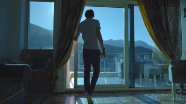 Slowmotion video. Romantic couple enjoing the view on mountains and sea from a balcony of their apartment.