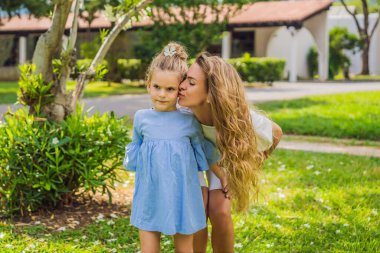 Yeşil Park 'ın dışında küçük tatlı kızıyla yürüyen genç ve güzel bir anne. Yaşam tarzı kavramı..