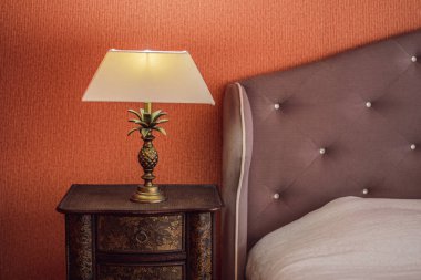 Modern bir yatak odasının köşesinde parlak bir eko ışık. Yeni öncü teknoloji geleneksel iç tasarımla birleşiyor. Lamba odada rahat bir atmosfer yaratıyor. Tahta, cam masa, mavi perdeler..