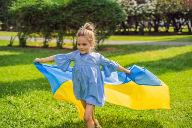 Ukrayna bayrağı taşıyan Ukraynalı bir kız. Dışarı çıkın. Avrupa 'da savaş sorunu kavramı, ailelerin ve çocukların desteği, göçmenler, göç, vatanseverlik, annelik.