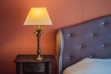 Modern bir yatak odasının köşesinde parlak bir eko ışık. Yeni öncü teknoloji geleneksel iç tasarımla birleşiyor. Lamba odada rahat bir atmosfer yaratıyor. Tahta, cam masa, mavi perdeler..