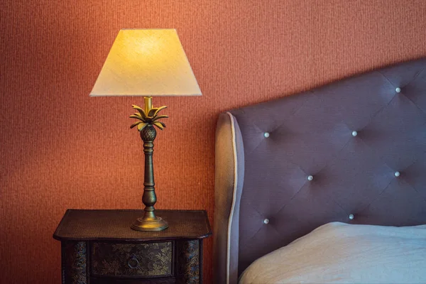 Modern bir yatak odasının köşesinde parlak bir eko ışık. Yeni öncü teknoloji geleneksel iç tasarımla birleşiyor. Lamba odada rahat bir atmosfer yaratıyor. Tahta, cam masa, mavi perdeler..