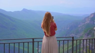 A young woman observes beautiful canyon of the Cijevna river on a way to the Grlo Sokolovo, a famous canyon at the Montenegro-Albania border. Travel to Montenegro concept.