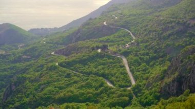 A handheld shot of the twisting road down from the mountains towards the city of Petrovac, a small coastal town in Montenegro. The country which is famous for its nature and rocky seashore.