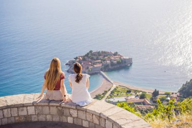 İki kadın turist, Karadağ 'ın Budva Riviera kentindeki St. Stephen adasının güzel manzarasına bakıyor. Karadağ 'a Seyahat.