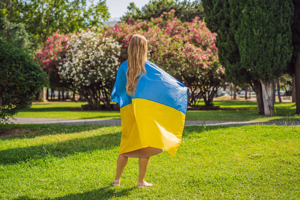 A woman put a Ukrainian flag on his shoulders. concept Ukrainian patriot, rally in support of Ukraine.