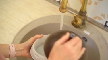 Genç bir kadın elektrikli aroma lambasını yıkıyor. Aromaterapi Konsepti. Elektronik Ultrasonik Temel Yağ Yayıcı ve Nemlendirici. Yakın çekim videosu.