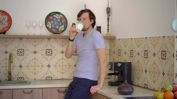Ένας Νεαρός Στην Κουζίνα Πίνει Καφέ Ένας Διαχύτης Αρωμάτων Στέκεται — Αρχείο Βίντεο