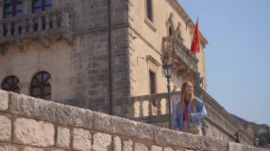 Boka-Kotorska körfezindeki güzel bir sahil kasabası olan Perast şehri kıyılarında genç bir kadın yürüyor..