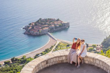 İki kadın turist, Karadağ 'ın Budva Riviera kentindeki St. Stephen adasının güzel manzarasına bakıyor. Karadağ 'a Seyahat.
