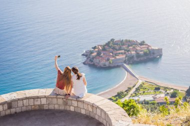 İki kadın turist, Karadağ 'ın Budva Riviera kentindeki St. Stephen adasının güzel manzarasına bakıyor. Karadağ 'a Seyahat.