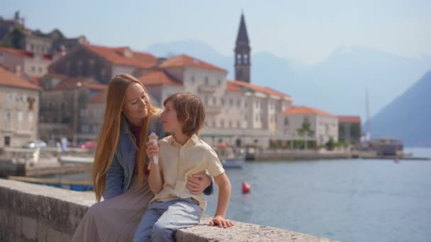 Eine Junge Frau Und Ihr Sohn Sitzen Auf Einer Mauer — Stockvideo