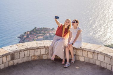 İki kadın turist, Karadağ 'ın Budva Riviera kentindeki St. Stephen adasının güzel manzarasına bakıyor. Karadağ 'a Seyahat.