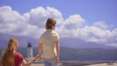 Genç bir kadın oğluyla birlikte Lustica Körfezi marinasında yürüyor. Karadağ 'a Seyahat.