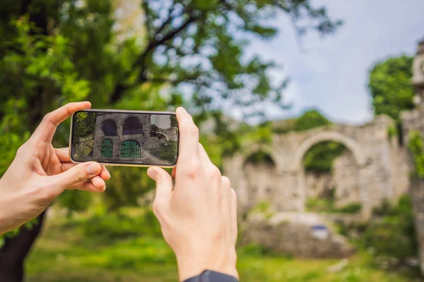 Augmented reality concept. Hand holding smart phone use AR application to check relevant information about building that was here in ancient times. Augmented reality in history and architecture.