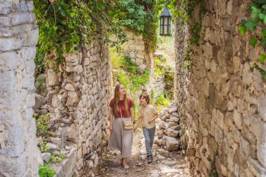 Anne ve oğul turistler Karadağ 'ın eski Bar kasabasından geçiyorlar. Dağlarda mutlu turist yürüyüşleri. Baro, Karadağ, Balkanlar 'ın banliyöleri. Güzel doğa ve manzara.