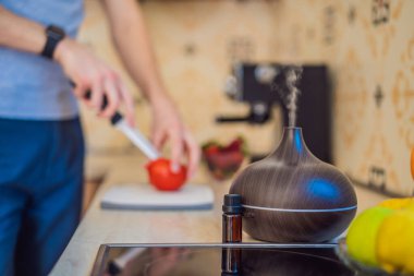 Bir adam aroma yayıcısının yanında yemek hazırlar. Aşçı mutfakta olgun kırmızı biber keser. Konuklar için taze, olgun, dolmalık biber salatası yapıyorum. Yaz taze sebze salatası.