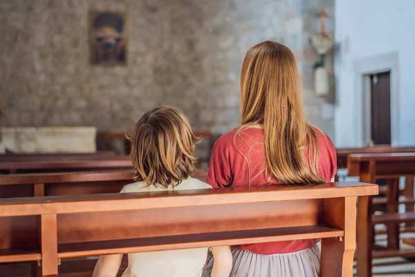 A Christian mom tells her son Bible stories about Jesus sitting in church. Faith, religious education, modern church, mothers day, maternal responsibilities, mothers influence on sons worldview