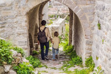 Baba ve oğul turistler Karadağ 'ın eski Bar kasabasından geçiyorlar. Dağlarda mutlu turist yürüyüşleri. Baro, Karadağ, Balkanlar 'ın banliyöleri. Güzel doğa ve manzara.