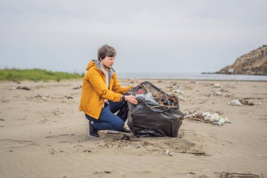 Plastik çöp. Deniz ve okyanus kirliliği. Plaj temizliği. Genç adam kumsalda kullanılmış plastik şişe topluyor. Çevreci aktivist çöp topluyor. Dünyamızı kurtar. Doğa koruması.