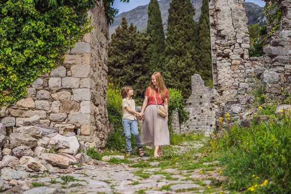 Anne ve oğul turistler Karadağ 'ın eski Bar kasabasından geçiyorlar. Dağlarda mutlu turist yürüyüşleri. Baro, Karadağ, Balkanlar 'ın banliyöleri. Güzel doğa ve manzara.