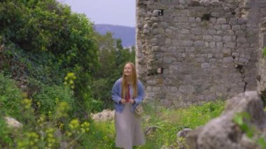 Genç bir kadın eski barın kalıntılarını ziyaret ediyor ya da Stari Grad 'ı. Baro şehrine yakın eski bir yerleşim yeri yok edildi. Karadağ 'ın tatil beldeleri. Bir el kamerası..