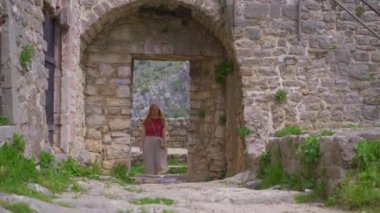 Genç bir kadın eski barın kalıntılarını ziyaret ediyor ya da Stari Grad 'ı. Baro şehrine yakın eski bir yerleşim yeri yok edildi. Karadağ 'ın tatil beldeleri. Bir el kamerası..