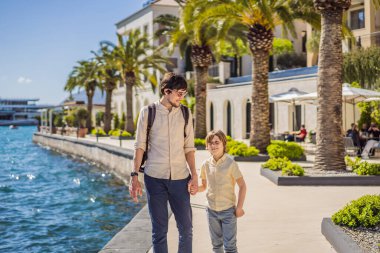 Baba ve oğul turistler Yat marinasının arka planında, güzel Akdeniz manzarası sıcak renklerde. Karadağ, Kotor Körfezi, Tivat şehri. Porto Karadağ yat limanı manzaralı. Her yere git. Dolaşın.