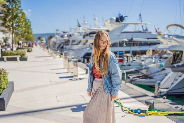 Woman tourist on background of Yacht marina, beautiful Mediterranean landscape in warm colors. Montenegro, Kotor Bay, Tivat city. Porto Montenegro marina view. Go Everywhere. Travel around Montenegro