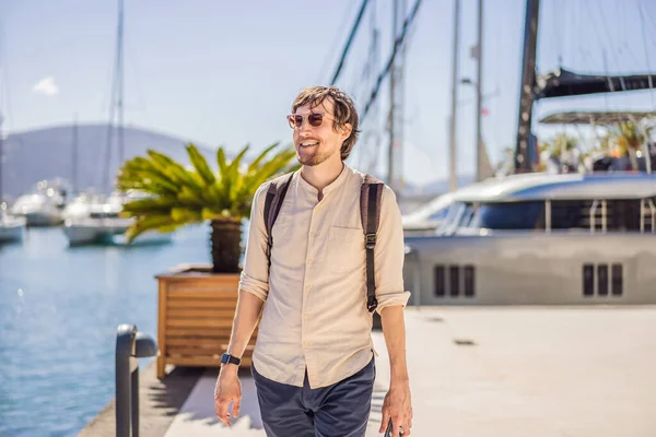 Man tourist on background of Yacht marina, beautiful Mediterranean landscape in warm colors. Montenegro, Kotor Bay, Tivat city. Porto Montenegro marina view. Go Everywhere. Travel around Montenegro