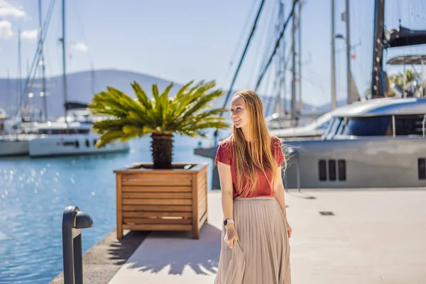 Woman tourist on background of Yacht marina, beautiful Mediterranean landscape in warm colors. Montenegro, Kotor Bay, Tivat city. Porto Montenegro marina view. Go Everywhere. Travel around Montenegro