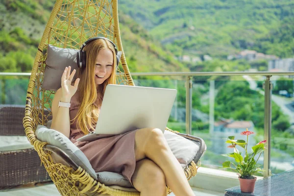 Caucasian woman sitting on the terrace working from home using computer laptop. Young woman teaches a foreign language or learns a foreign language on the Internet on her balcony. Online language
