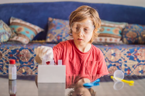 小男孩在家里做化学实验 戴防护眼镜的儿童学习使用滴注液体检测试管 高加索 生物化学 化学课 家庭学校概念 — 图库照片