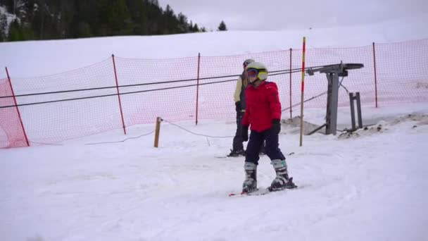 女と息子はスキーの勉強をしている 彼らはスキーエレベーターを使って丘を上り トレーニングコースを下ります — ストック動画