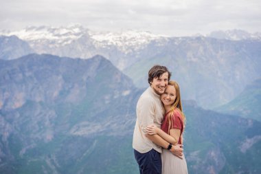 Erkek ve kadın, Karadağ 'daki Grlo Sokolovo boğazının nefes kesici panoramik manzarasının arka planında yaşayan mutlu çift turistler. Ön planda bir dağ var. Düz tarafı bir uçurum oluşturuyor.