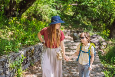 Anne ve oğul turistler Ostrog tapınağına tırmanırlar. Ostrog Manastırı, Sırp Ortodoks Kilisesi, Ostroska Greda 'nın büyük kayasının tepesinde dikey bir arka plana karşı yer alıyor.