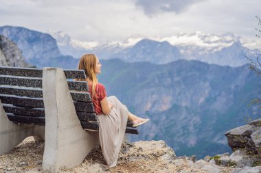Karadağ 'daki Grlo Sokolovo vadisinin nefes kesici panoramik manzarasının arka planındaki kadın turist. Ön planda bir dağ var. Düz tarafı bir uçurum oluşturuyor. Tepe de tamamen büyümüş.